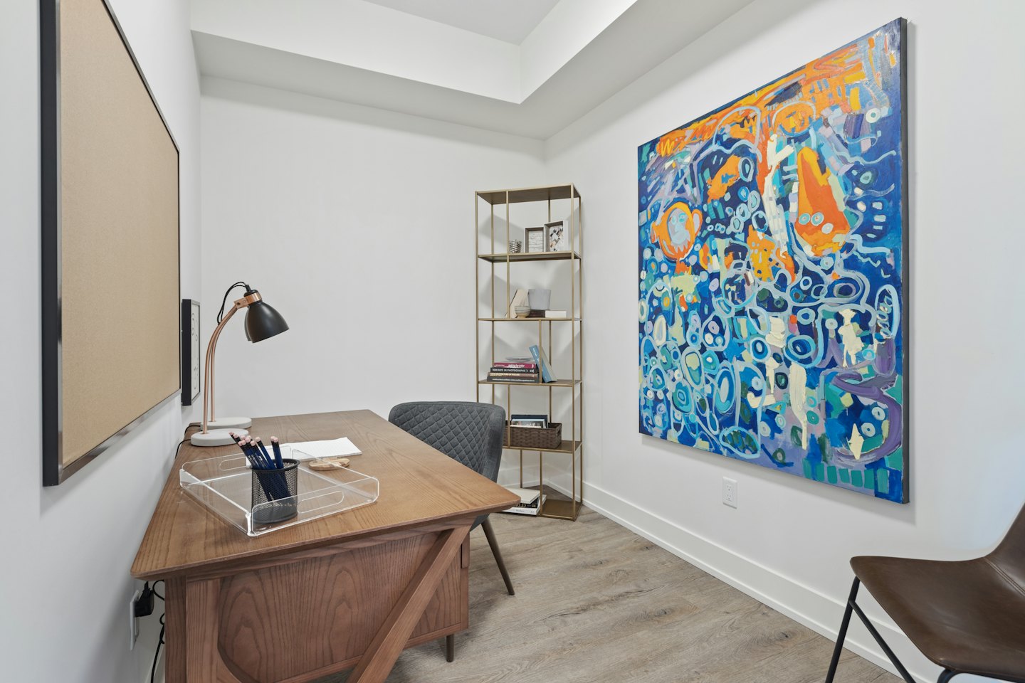 Modern home office with a wooden desk and abstract art.