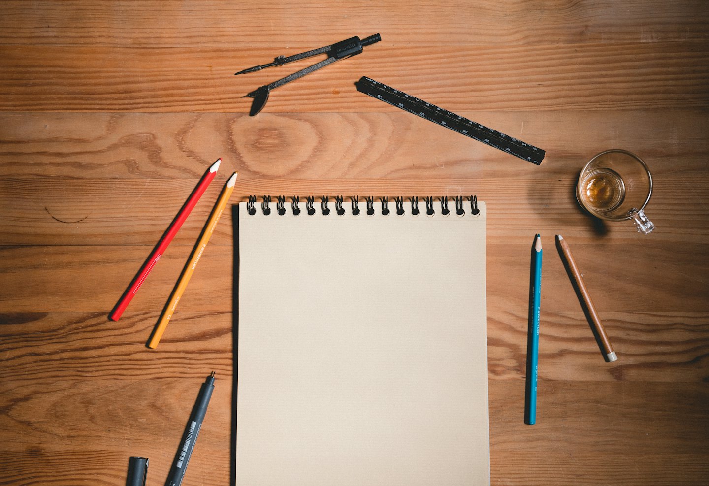 Art and design tools laid out on a rustic wooden desk.