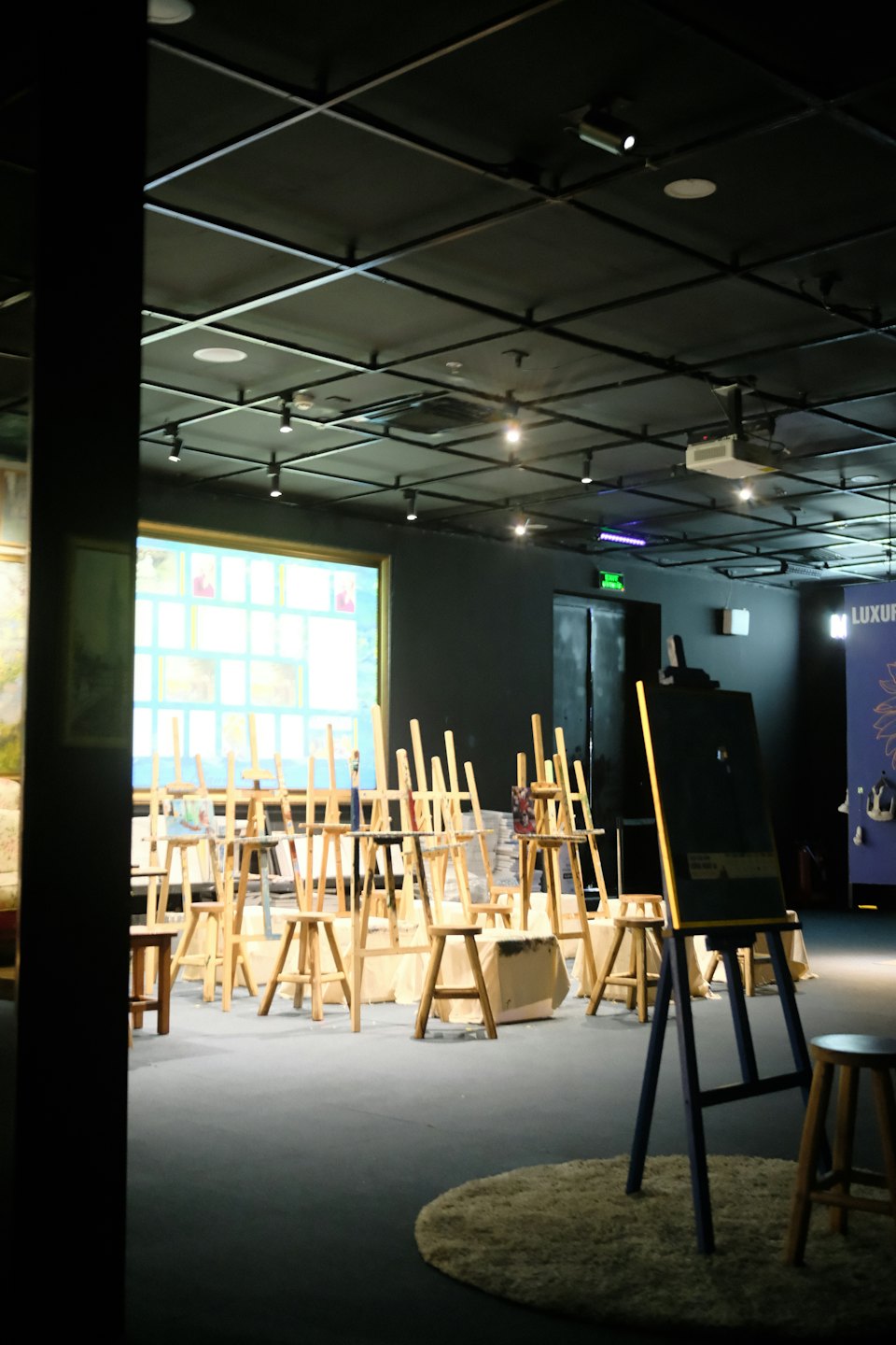 Empty art studio with wooden easels and a projection screen.