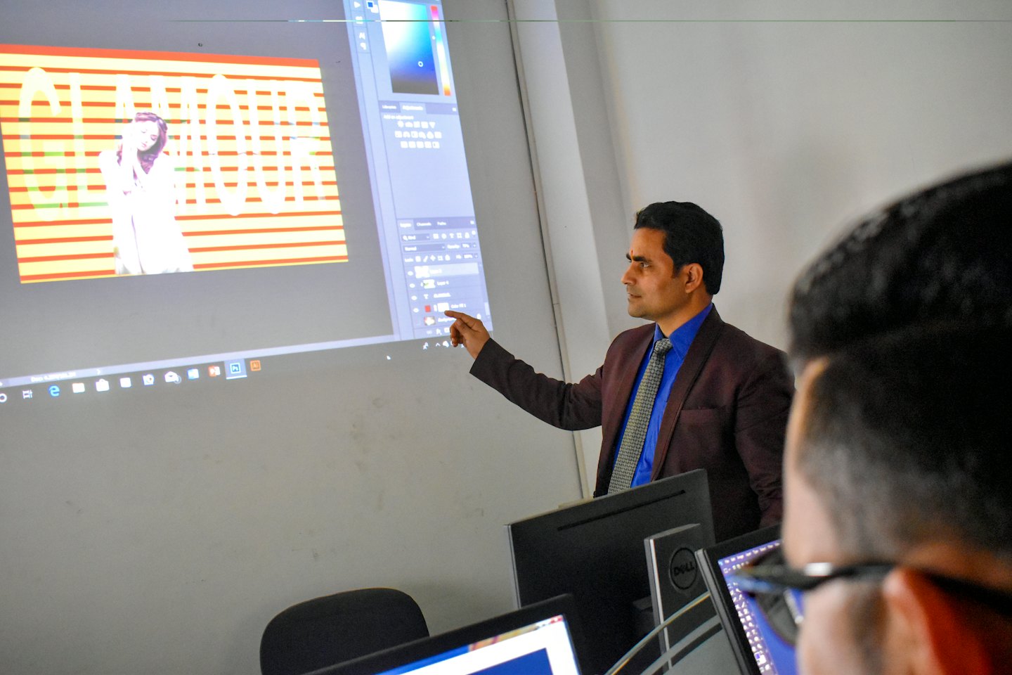 Man in suit points to screen showing Photoshop software.